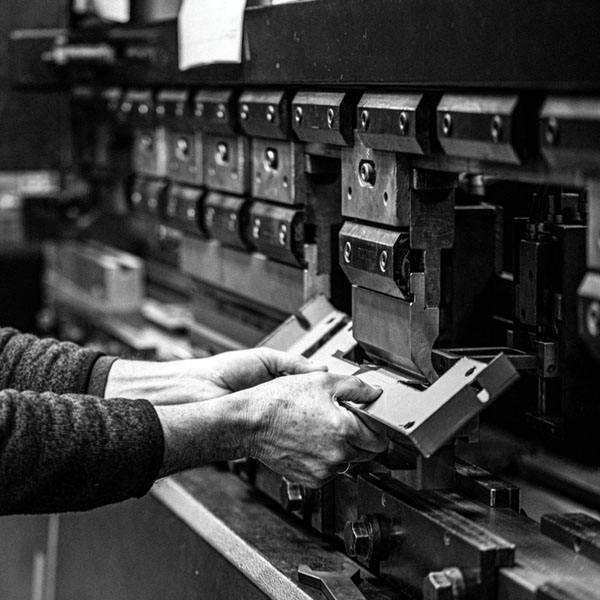 A black and white photo of a man working on a machine with precision manufacturing services.