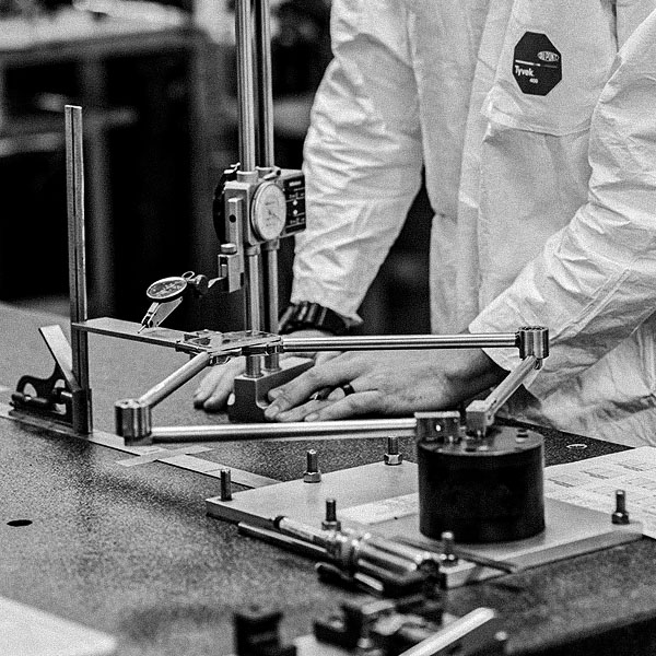 A man in a lab coat providing precision manufacturing services while working on a machine.
